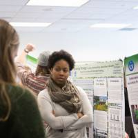 Attendees view a student group's poster presentation.